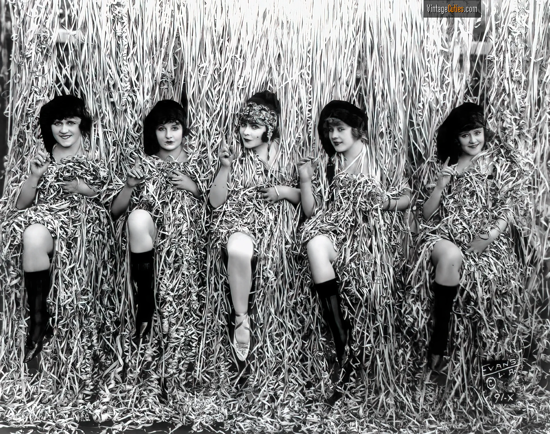 A bunch of burlesque ladies hide behind hanging straps
