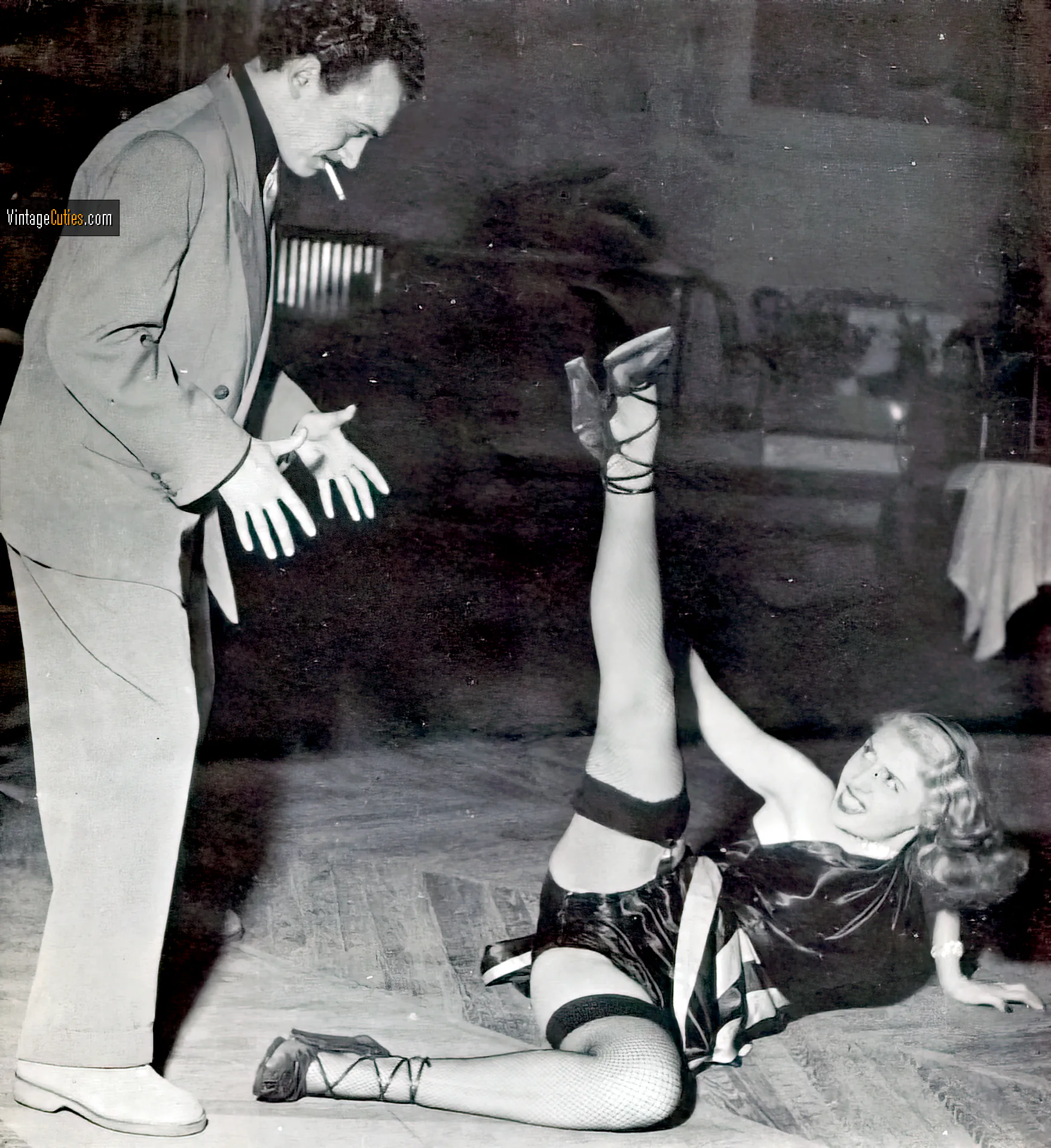 Sexy burlesque babe lies on the floor, shows her long leg to her man