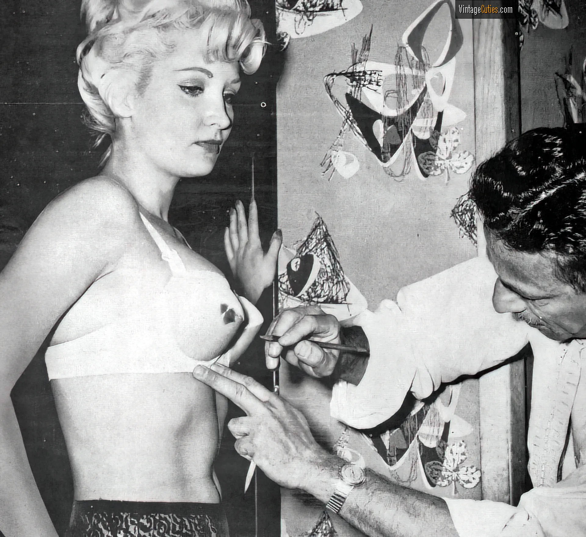 Dreamy burlesque blonde with a man drawing on her white bra
