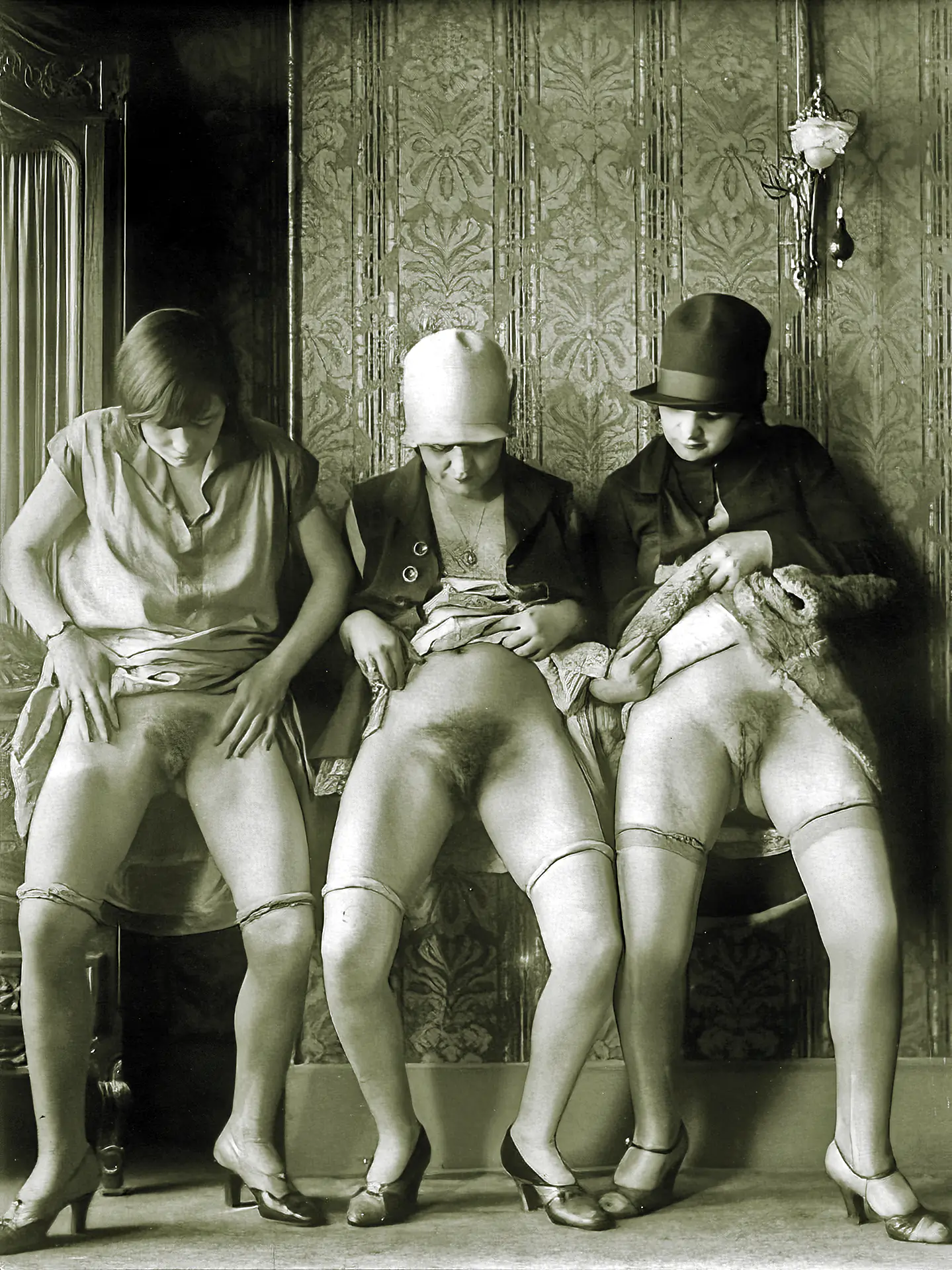 Vintage Vaudeville porn photos with three women wearing hats lifting their skirts up to expose their massively hairy pussies indoors